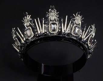 May include: A black crown with silver spikes and spider accents. The crown is adorned with clear rhinestones.
