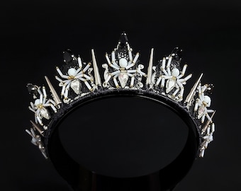 May include: A black crown with silver spikes and white spider embellishments.
