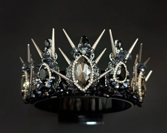 May include: A black crown with silver spikes and black gemstones. The crown has a black velvet band and a large, faceted black gemstone in the center.