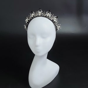 May include: A black headband with a silver crown of spiders. The spiders have white pearl accents.