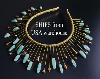 May include: A gold headband with a row of light green oval-shaped stones and gold stars hanging from it. The headband is decorated with gold thread and the text "SHIPS from USA warehouse" is visible in the center.