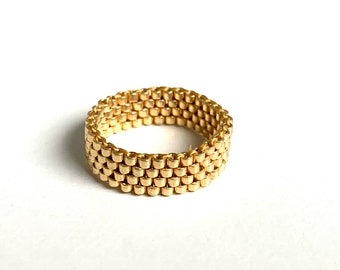May include: A gold-colored ring made of small, linked squares.