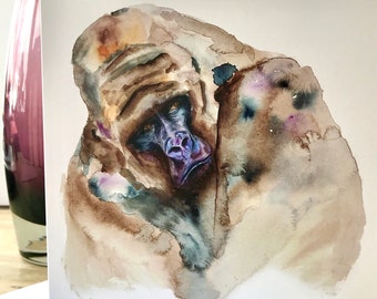 May include: Watercolor painting of a gorilla's face. The artwork features shades of brown, gray, and blue, with a focus on the gorilla's expressive features. The card is square and has a white border.