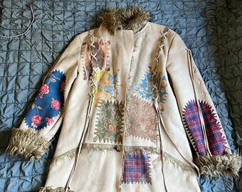 Könnte beinhalten: Eine cremefarbene Jacke mit Kunstpelzbesatz und Patchwork-Design mit Blumen- und Karomustern.