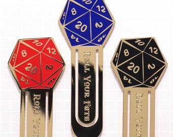 May include: Three gold metal bookmark designs featuring a 20-sided die in blue, red, and black. Each bookmark has the text "Roll Your Fate" engraved on the side.