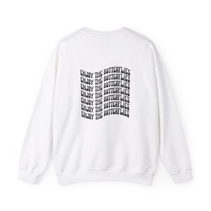 May include: White sweatshirt with a black graphic print that says "Enjoy the Butterflies" repeated multiple times.