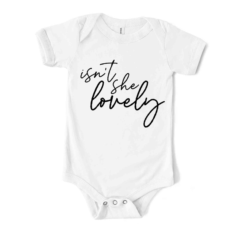 May include: White baby bodysuit with short sleeves. The text "isn't she lovely" is printed in black cursive script across the front. The bodysuit has a snap closure at the bottom.