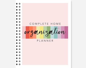 May include: A spiral-bound planner with a light pink cover. The cover features the text "COMPLETE HOME ORGANIZATION PLANNER" in black and a rainbow-colored stripe. The words "Digital PDF download" are at the top.