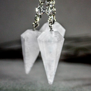 May include: Two clear crystal pendulum points hanging from a silver chain with crystal beads.