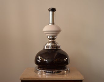 May include: A black and white ceramic table lamp with a chrome base and a round, dark brown glass shade.