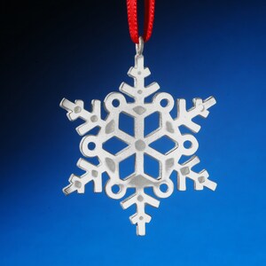 May include: A silver snowflake ornament with a red ribbon attached to the top.
