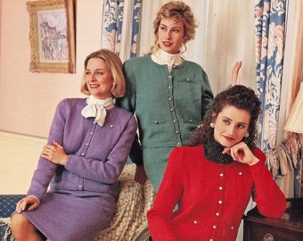 May include: Three women wearing cardigans. The woman on the left is wearing a purple cardigan and skirt. The woman in the middle is wearing a green cardigan and skirt. The woman on the right is wearing a red cardigan and black trousers.