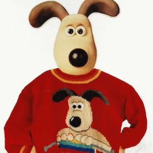 May include: A red knitted sweater with a yellow and orange trim. The sweater features a knitted image of a dog holding knitting needles and a rainbow colored yarn.