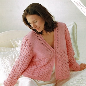 Peut inclure: Un cardigan rose en tricot avec un col en V et une fermeture boutonnée. Le cardigan présente un motif de dentelle délicat et est porté sur une robe en satin blanche. L'image comprend également une paire de chaussettes roses en tricot avec une bordure en dentelle.