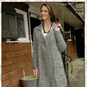May include: A grey knitted cardigan with a button fastening and a large pocket. The cardigan is 76 cm long and 107 cm wide. The model is wearing the cardigan with a white shirt and a necklace. The image also includes the text "EASY KNIT 5429 PRICE CODE G 76-107 cm 30-42 ins ZENA".