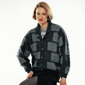 Puede incluir: Una mujer con un cárdigan de patrón gris y negro, una falda negra y medias grises. Está sentada en una silla plateada.