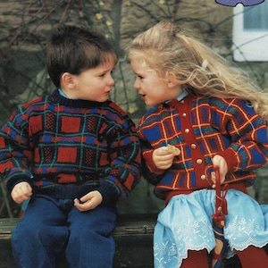 Könnte beinhalten: Zwei Kinder in rot-blauen Karopullovern sitzen auf einer Holzbank. Das Mädchen hält einen Keks in der Hand und der Junge schaut sie an.