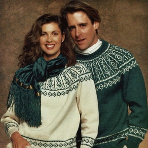 Peut inclure: Un couple portant des pulls assortis crème et vert à motifs. La femme porte une écharpe verte avec des accents dorés. L'homme porte un pantalon beige.