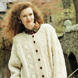 May include: A cream-coloured cable knit cardigan with a button-up front. The cardigan has a relaxed fit and is made of a soft, warm material.