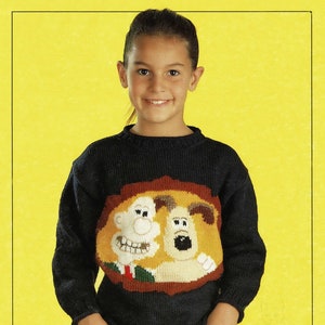May include: A child wearing a dark blue knitted jumper with a cartoon image of Wallace and Gromit. The jumper has a crew neck and long sleeves.