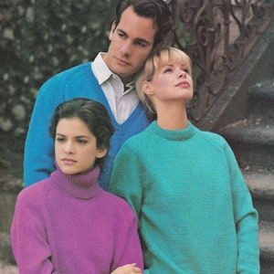 Op de afbeelding: Drie mensen dragen truien. De persoon links draagt een paarse trui met een hoge hals. De persoon in het midden draagt een turquoise trui. De persoon rechts draagt een blauwe trui met een wit shirt eronder.