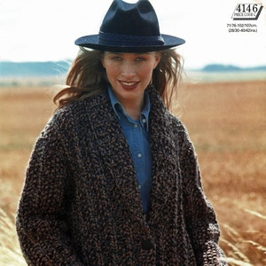 May include: A brown and black knitted cardigan with a button closure and two pockets. The cardigan is worn by a person wearing a blue shirt and a black hat.