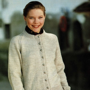 May include: A light beige cardigan with a round neckline and button closure. The cardigan has a ribbed texture and is made of a soft, knitted fabric.