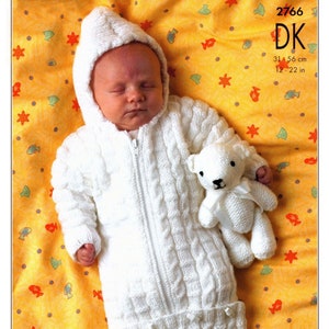 May include: White knitted baby sleeping bag with a hood and a zip fastening. The sleeping bag has a cable knit pattern and a pocket at the bottom. A white knitted teddy bear is lying next to the baby. The pattern number 2766 DK is printed in the top right corner of the image. The size is 31-56 cm or 12-22 in.