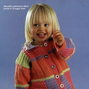 May include: A young child wearing a colorful knitted cardigan with a patchwork design. The cardigan has a button closure and is made with different shades of pink, purple, green, and yellow yarn.