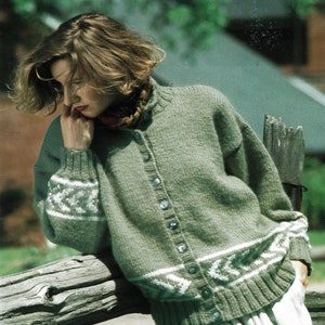 Op de afbeelding: Een vrouw draagt een groene gebreide cardigan met witte bies en een witte rok. De cardigan heeft een knoopsluiting aan de voorkant en is gemaakt van zacht, getextureerd garen.