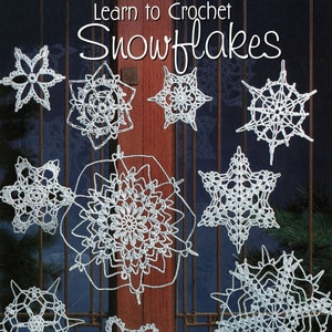 May include: A book titled "Learn to Crochet Snowflakes" with a white ball of yarn and a crochet hook. The cover features a variety of crocheted snowflakes in white against a dark blue background.