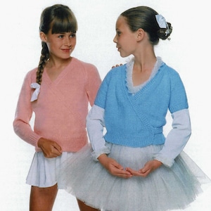 May include: Two young girls wearing knit sweaters and white skirts. The girl on the left is wearing a pink sweater and the girl on the right is wearing a light blue sweater. Both girls are looking at each other.