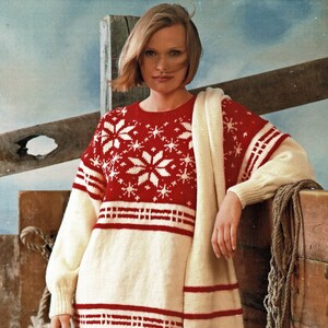 Puede incluir: Un suéter de punto blanco y rojo con un patrón de copo de nieve y una bufanda a juego. El suéter tiene cuello redondo y mangas largas. La bufanda tiene flecos en los extremos.