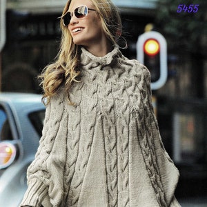 May include: A beige cable knit poncho with a high neck and long sleeves. The poncho is made of a soft, warm yarn and has a relaxed fit.