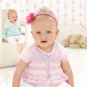 May include: A baby wearing a pink and white striped knitted cardigan with a button fastening. The cardigan has a frilled hem and short sleeves. The baby is wearing a white lace skirt and a pink headband with a flower.