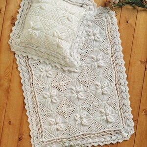 May include: A white crocheted blanket and pillow set with a delicate floral pattern. The set is made with a fine yarn and features a lacy border.