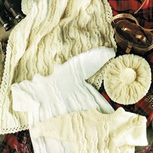 Peut inclure: Un ensemble de trois articles tricotés en blanc : une couverture pour bébé, un pull et un bonnet. La couverture présente un motif en tricot torsadé et une bordure en crochet. Le pull a un motif en tricot torsadé et un col rond. Le bonnet a un motif en tricot torsadé et un pompon sur le dessus.
