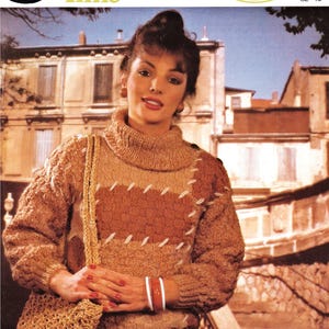 Puede incluir: Una mujer con un jersey de punto marrón y beige con cuello alto y un bolso de punto a juego. El jersey tiene un patrón texturizado y detalles de costura blancos. También se ve el texto "Leisure Time" y "Lightweight Chunky".