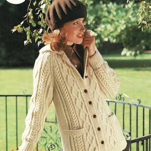 May include: A white cable knit cardigan with a brown button closure and two patch pockets. The cardigan is worn by a person with brown hair wearing a brown beret. The image has the text "Sunbeam" and "Aran 86 - 102 cm bust 34 - 40 ins" and the number "286".