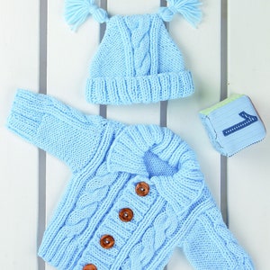 May include: A light blue knitted baby cardigan with wooden buttons and a matching light blue knitted hat with two pom-poms.