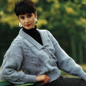 May include: A light blue knitted cardigan with a cable knit pattern and a button closure. The cardigan has a v-neck and long sleeves.