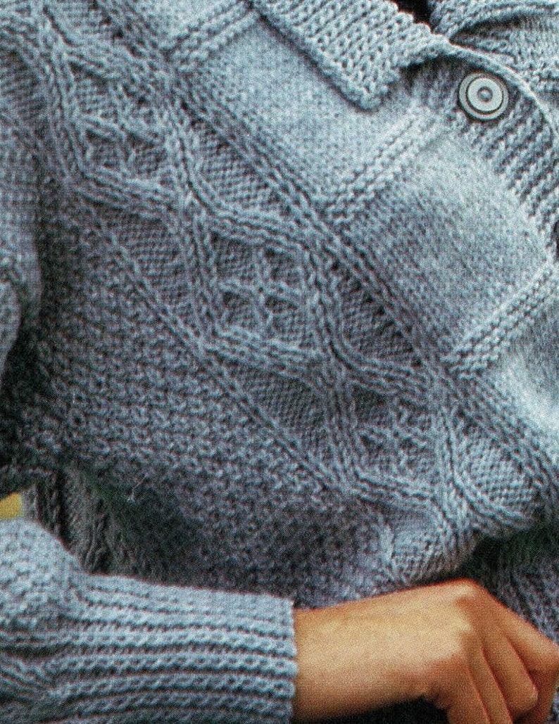 May include: A close-up of a blue knitted cardigan with a cable knit pattern and a button closure.