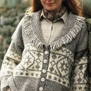 May include: A brown and white knitted cardigan with a fringe trim collar and button closure. The cardigan has a geometric pattern and is worn over a light brown shirt.