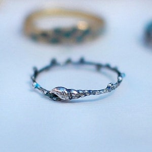 Puede incluir: Un anillo de plata con un diseño de rama y un detalle de hoja. El anillo está hecho de metal y tiene un aspecto rústico.