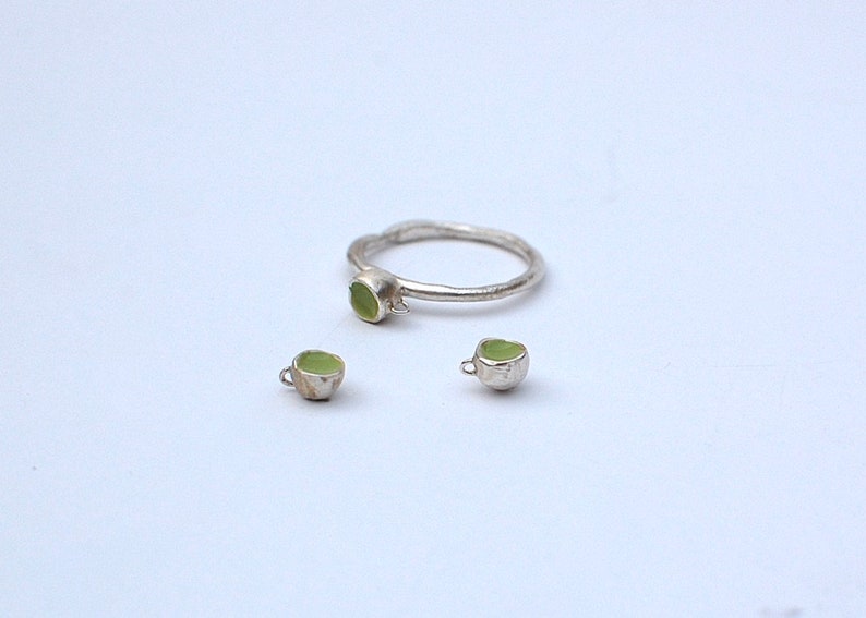 Peut inclure: Un ensemble de bijoux en argent avec des pierres vertes. L'ensemble comprend une bague et une paire de boucles d'oreilles.