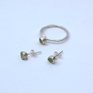 Peut inclure: Un ensemble de bijoux en argent avec des pierres vertes. L'ensemble comprend une bague et une paire de boucles d'oreilles.