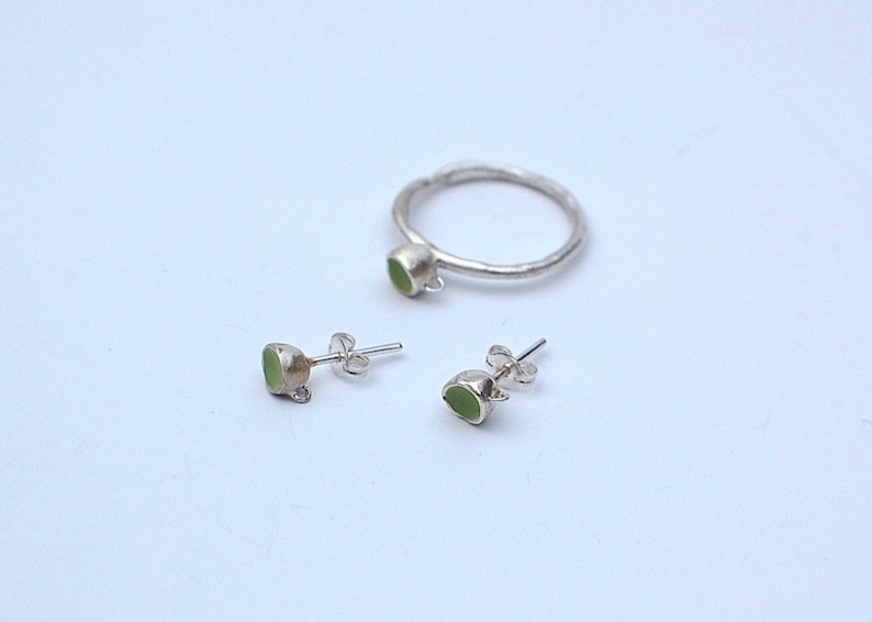 Peut inclure: Un ensemble de bijoux en argent avec des pierres vertes. L'ensemble comprend une bague et une paire de boucles d'oreilles.