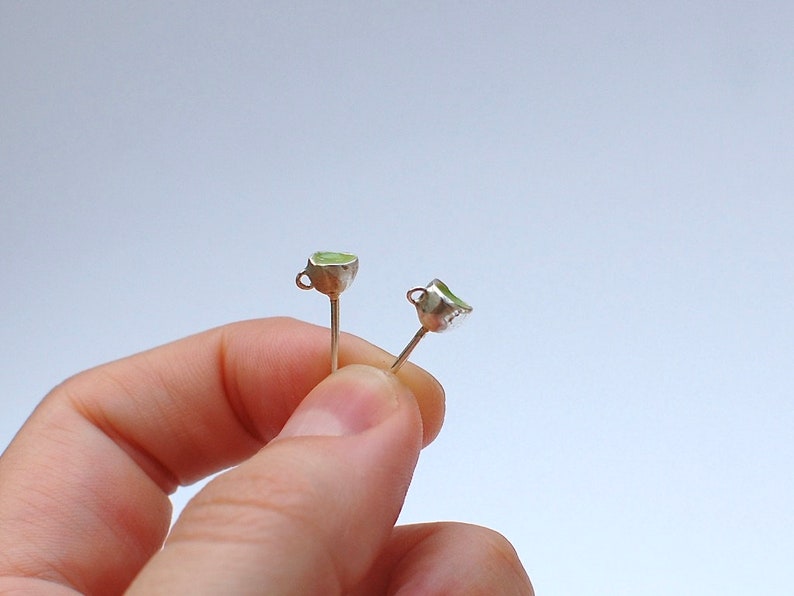 Peut inclure: Une paire de boucles d'oreilles en argent avec de petites tasses vertes attach&eacute;es aux extr&eacute;mit&eacute;s.