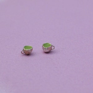 Peut inclure: Deux tasses &agrave; th&eacute; miniatures avec des poign&eacute;es argent&eacute;es et des int&eacute;rieurs en &eacute;mail vert. Les tasses sont sur un fond violet clair.