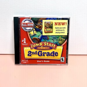 May include: A Jump Start Advanced 2nd Grade educational software CD-ROM. The cover is red and yellow with a cartoon dog wearing glasses. The CD case has the text "NEW! Explore your world and discover its amazing animals!"